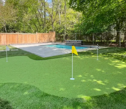 A putting green installed in the backyard of a client's home in Etobicoke next to their pool