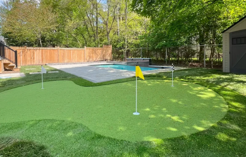 A putting green installed in the backyard of a client's home in Etobicoke next to their pool