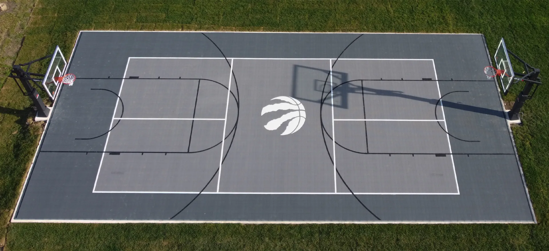 An aerial view of a grey custom Toronto Raptors backyard basketball court installed by Elite Courts.