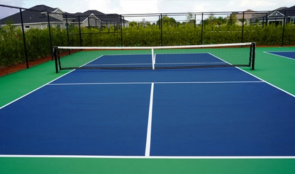 A pickleball court installed in the backyard of a person's home with fencing around it