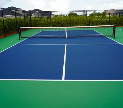 A pickleball court installed in the backyard of a person's home with fencing around it