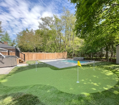 A putting green installed in the backyard of a client's home in Etobicoke next to their pool