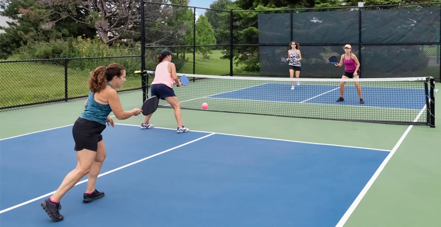 4 women playing pickleball together