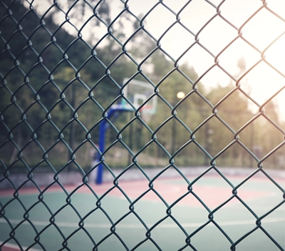 View of a basketball court through the fencing around it