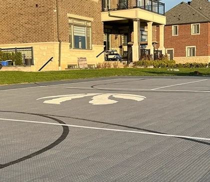 A grey Toronto Raptors custom backyard basketball court installed by Elite Courts in Caledon, Ontario.