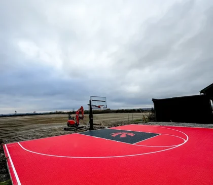 Red custom design Raptors backyard basketball court being installed by the Elite Courts Team.
